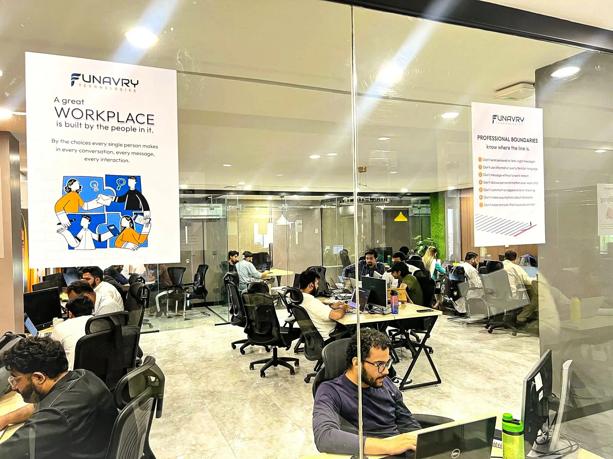 Funavry engineers at work across the open-plan office floor, seen through the glass partitions of the workspaces