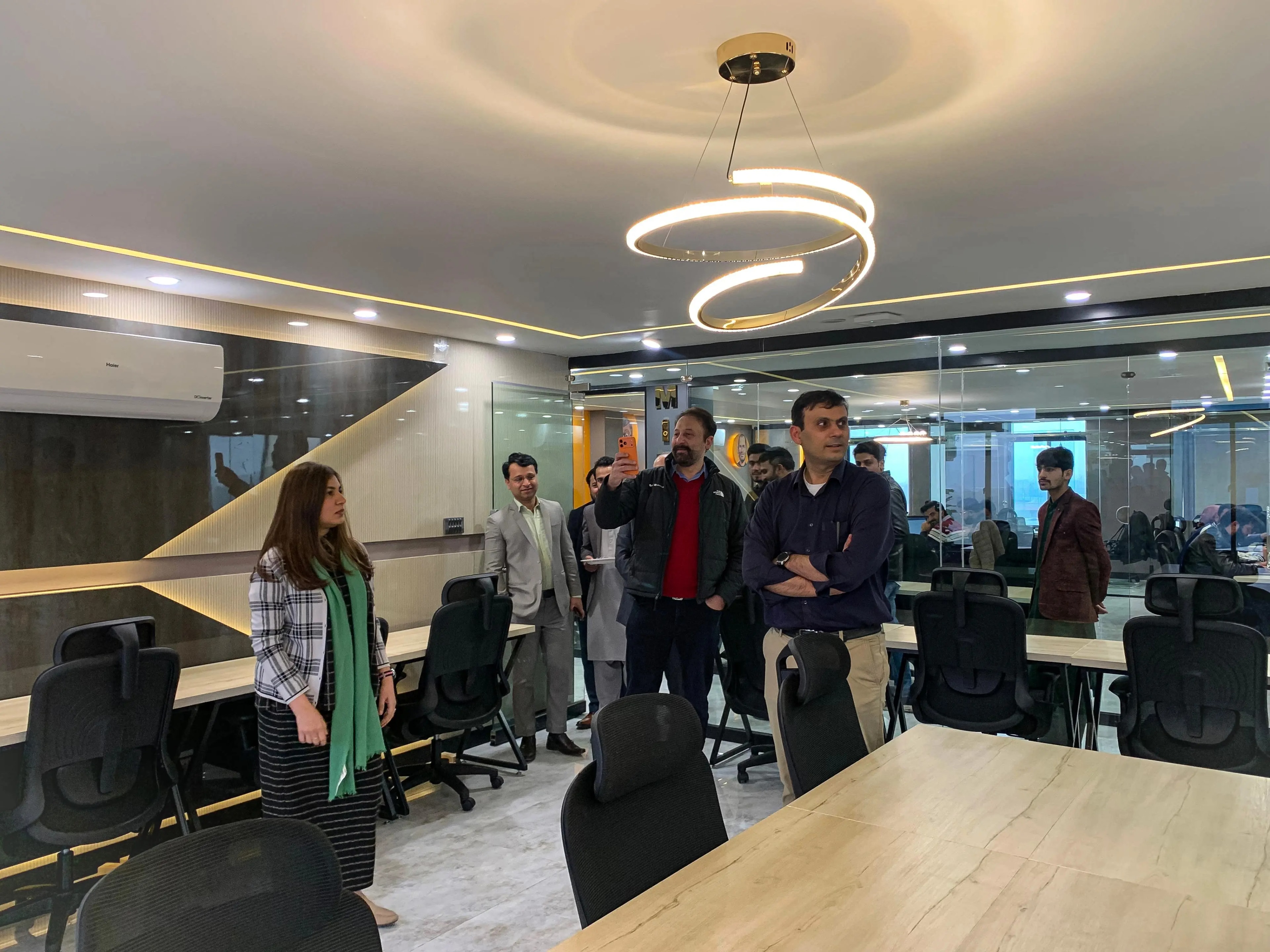 Valued clients being shown around a meeting room at the office, beneath a spiral pendant light